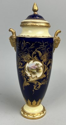 Lot 653 - A COALPORT PORCELAIN URN AND COVER WITH CENTRAL PAINTED LANDSCAPE SCENE, GILT RAMS HEAD HANDLES AND DETAILING ON BLUE GROUND