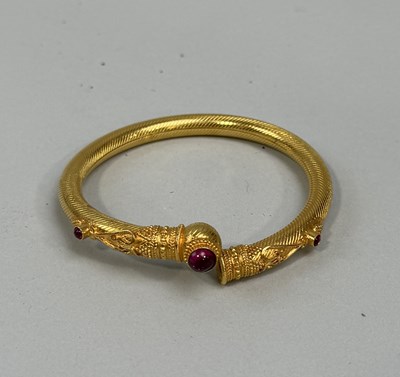 Lot 174 - AN INDIAN GOLD TONE BANGLE WITH RED STONES