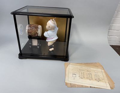 Lot 1014 - A JAPANESE CERAMIC MODEL OF A CHILD HITTING A DRUM, IN GLASS CASE