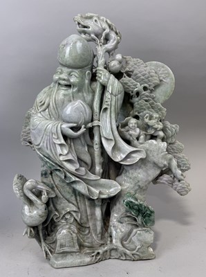 Lot 151 - A CHINESE JADE OR JADEITE SCULPTURE DEPICTING THE LUOHAN WITH A DRAGON STAFF, CHILDREN, CRANES AND FOLIAGE IN THE BACKGROUND