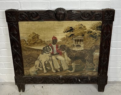 Lot 1075 - A VICTORIAN CARVED PANEL WITH NEEDLEPOINT EMBROIDERY DEPICTING AN AFRICAN GENTLEMAN SEATED WITH TWO DOGS