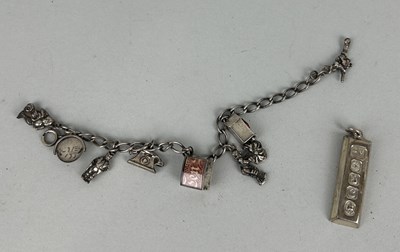 Lot 186 - A SILVER CHARM BRACELET ALONG WITH A SILVER INGOT