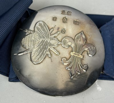 Lot 20 - A QEII SILVER BELT BUCKLE WITH BEE AND FLEUR DU LYS MOTIF, CLOTH STRAP