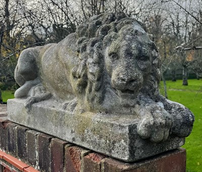 Lot 62 - A PAIR OF RECUMBENT STONE LIONS, reconstituted...