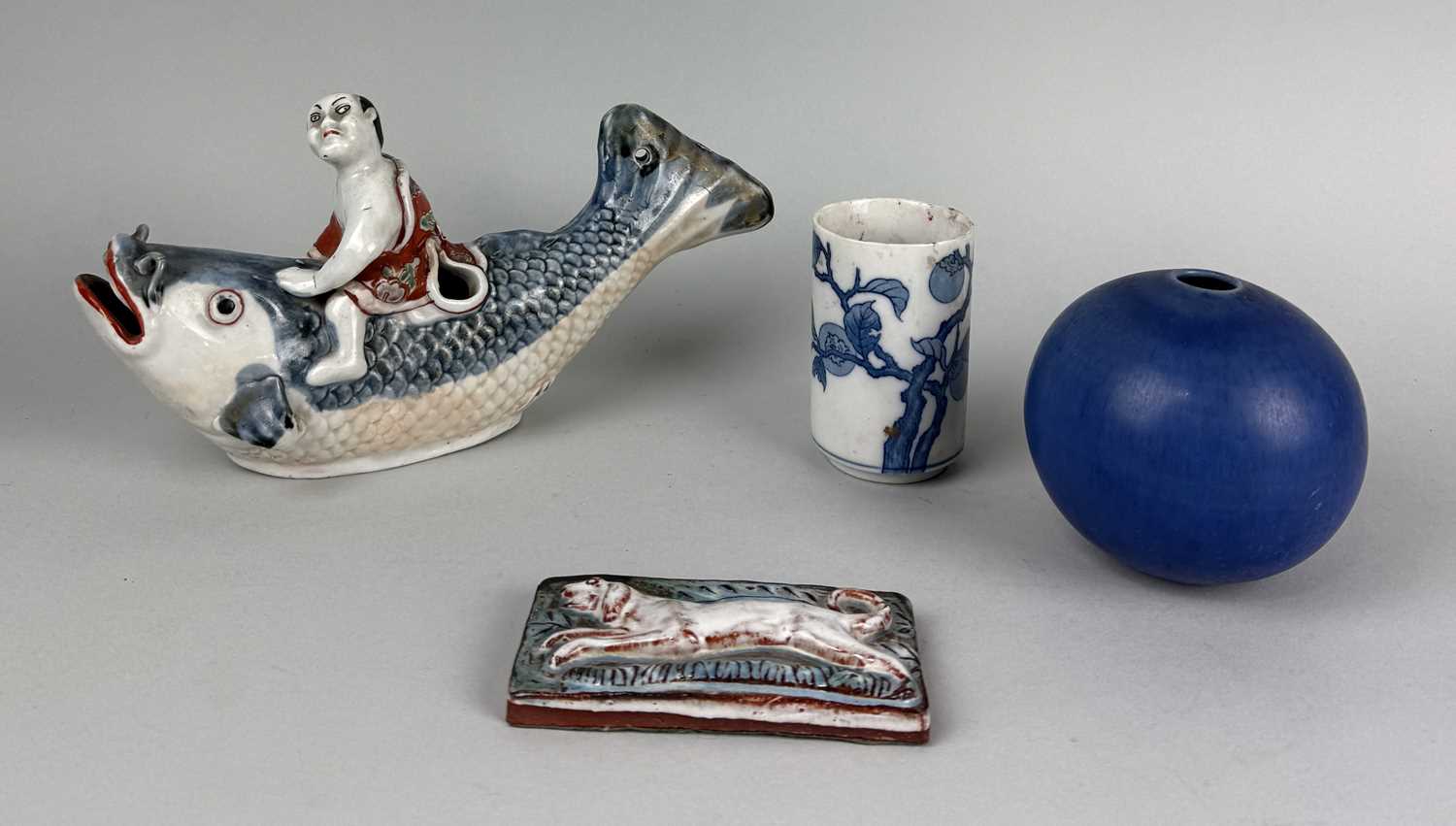 Lot 319 - A JAPANESE ARITA STYLE BOY RIDING A CARP ALONG WITH A BLUE GLAZED CERAMIC BOWL, CHINESE BRUSH POT AND GLAZED DOG RELIEF