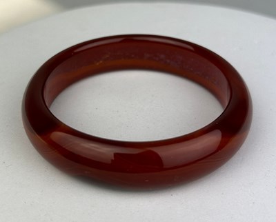 Lot 102 - A RED AGATE BANGLE, 

55gms